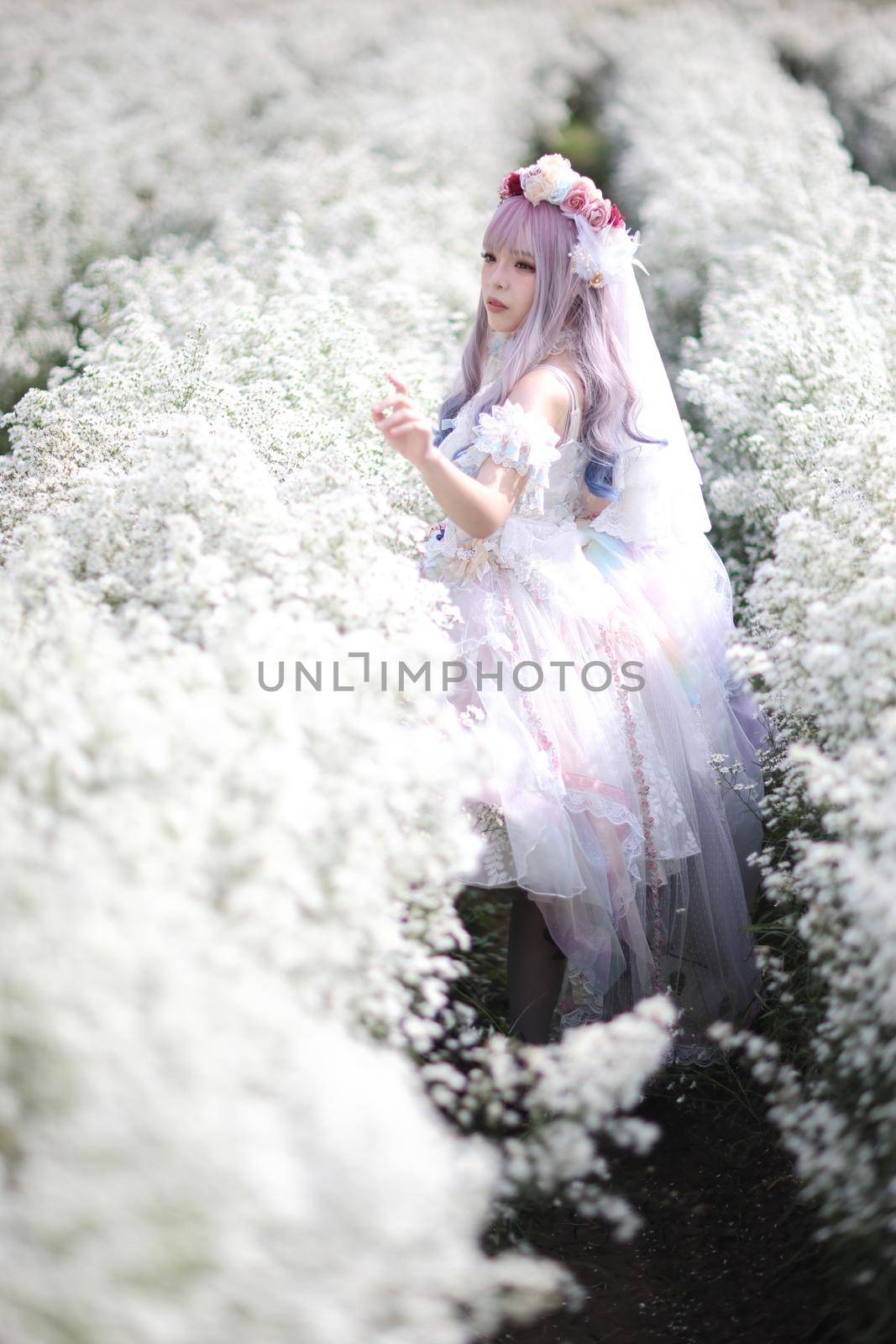 Beautiful young woman with white lolita dress with flowers garden Japanese fashion by piyato