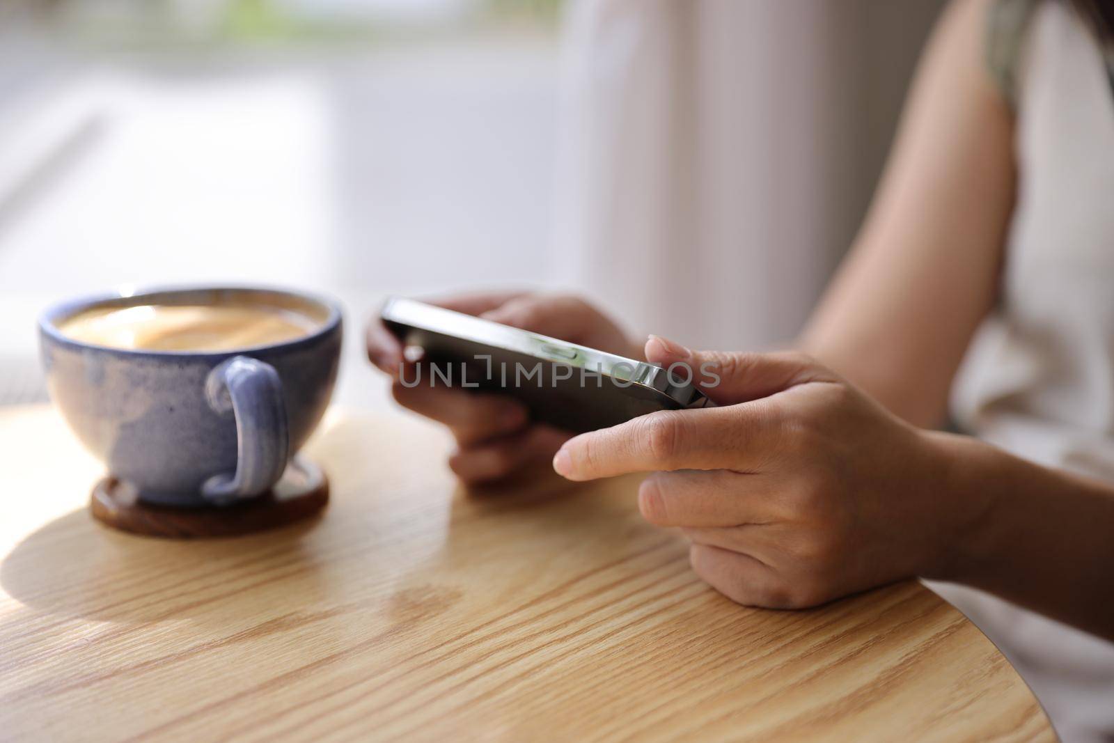 Woman hand using a smartphone for Stock exchange trading online in the coffee shop, business concept by piyato