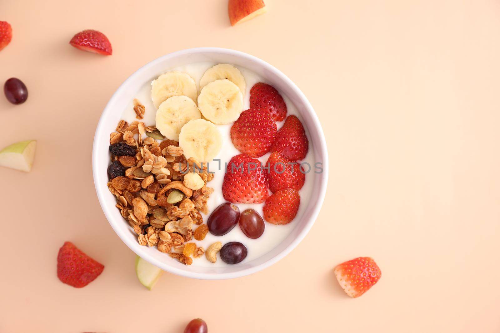 bowl of granola cereal with yogurt and berries isolated on eggnog color background