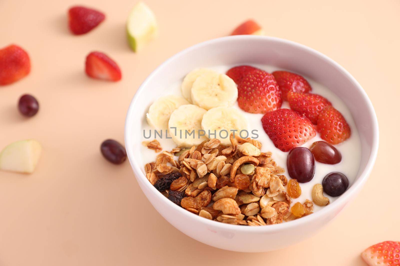 bowl of granola cereal with yogurt and berries isolated on eggnog color background