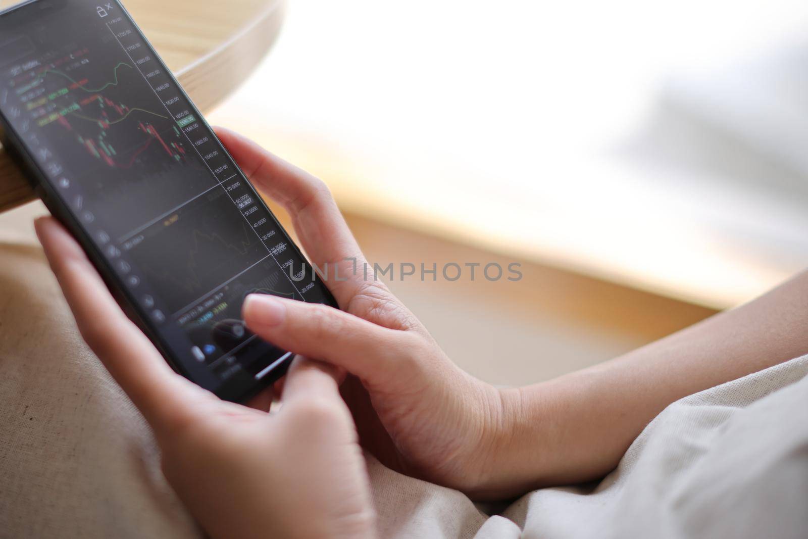 Woman hand using a smartphone for Stock exchange trading online in the coffee shop, business concept by piyato