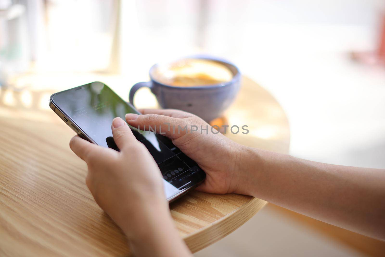 Woman hand using a smartphone for Stock exchange trading online in the coffee shop, business concept by piyato