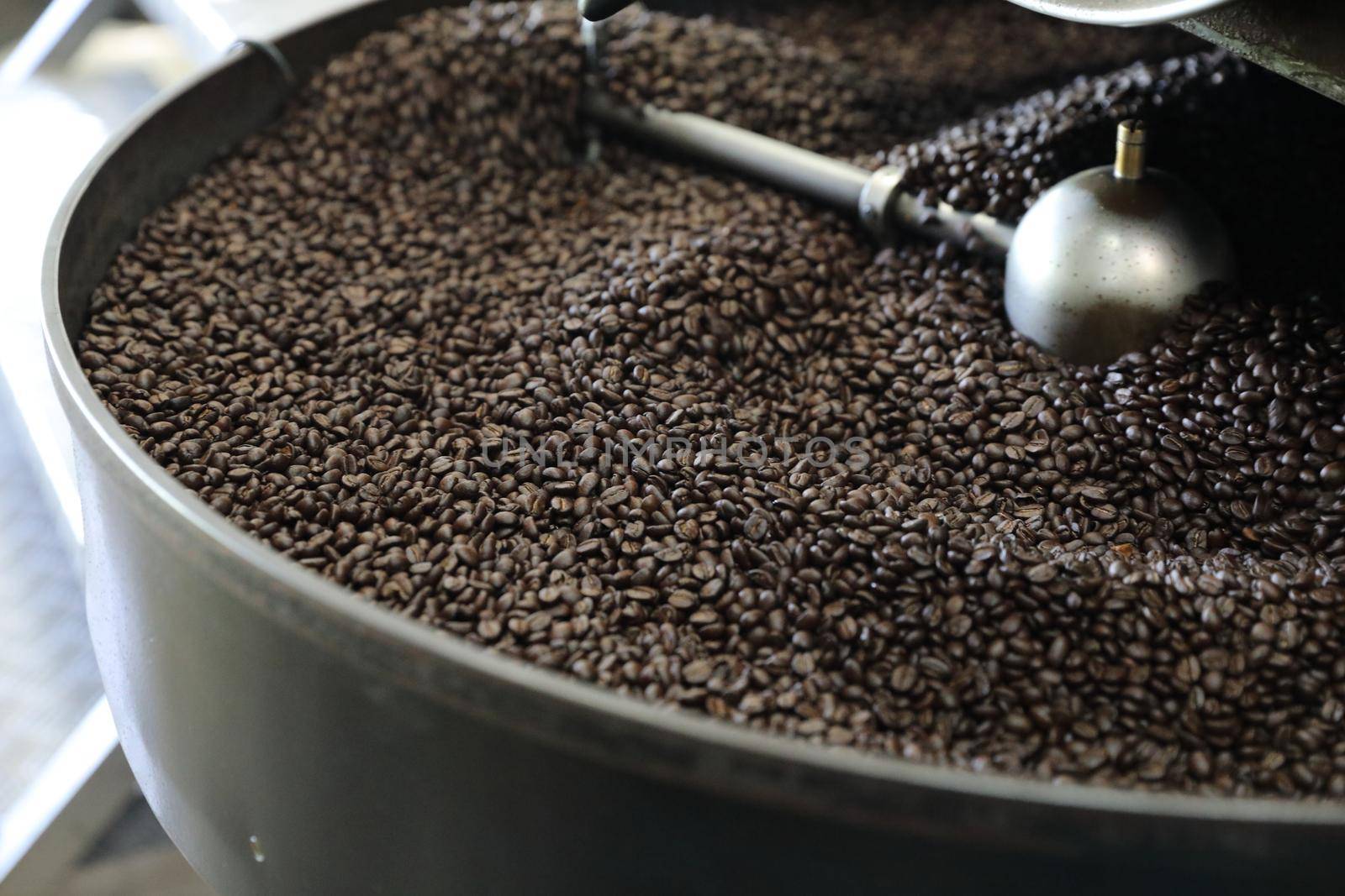 Coffee beans roasting with machine in close up by piyato