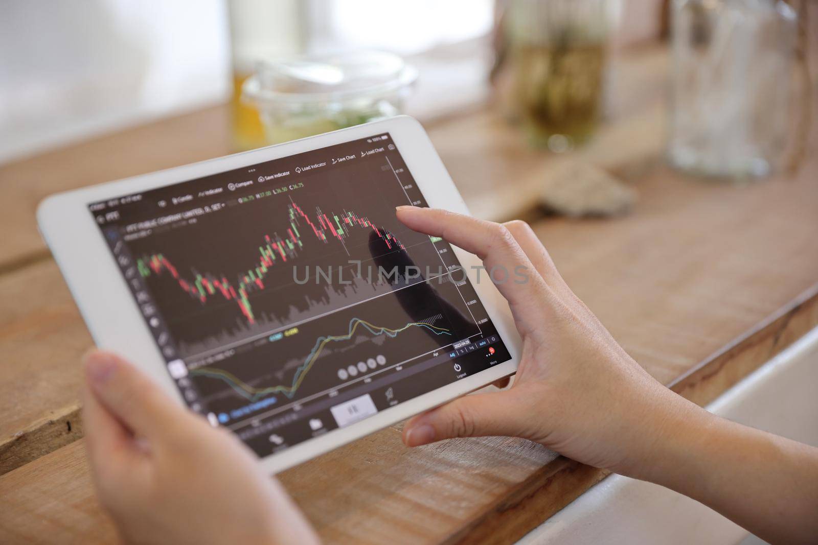 Woman hand using a tablet for Stock exchange trading online in the coffee shop, business concept by piyato