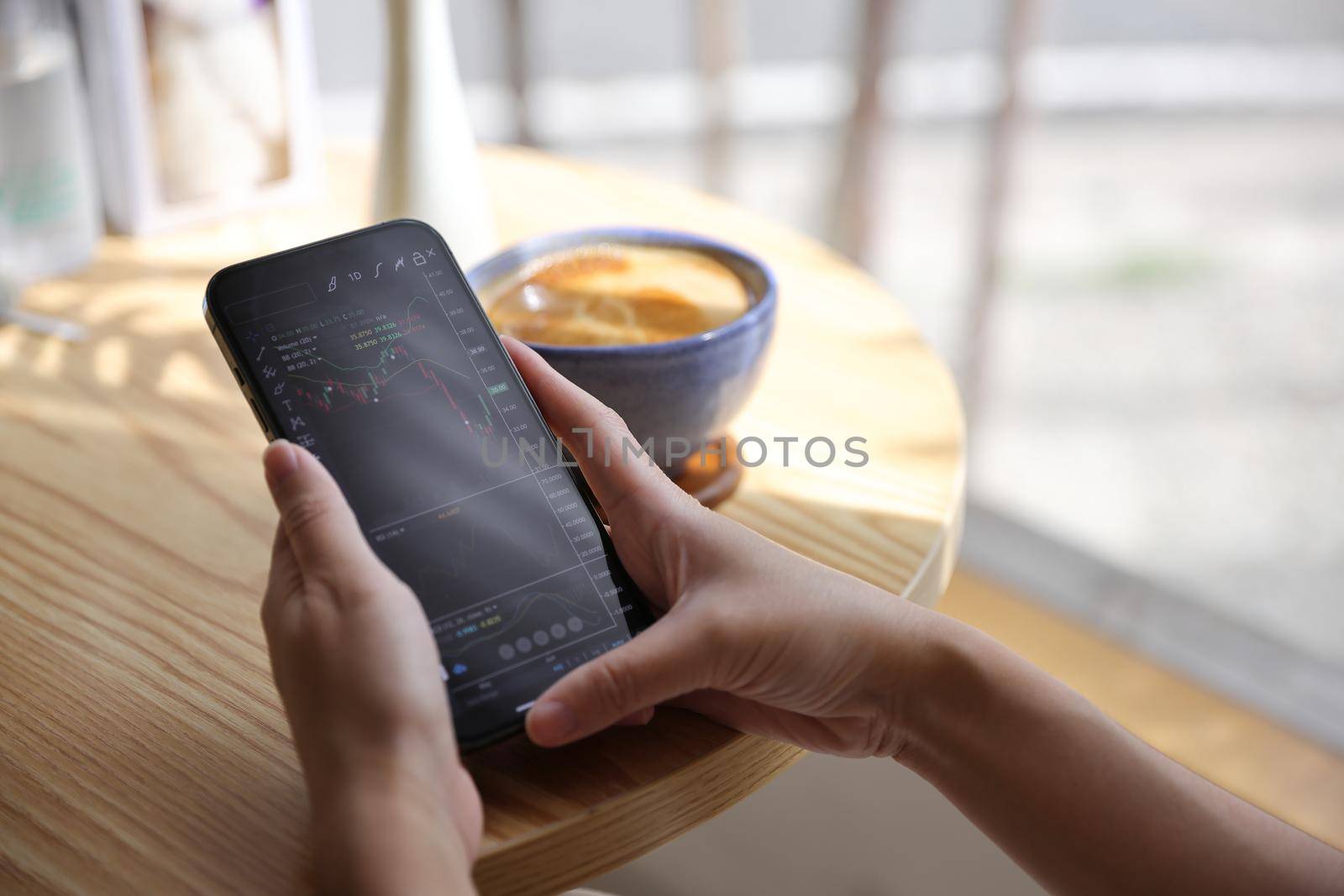 Woman hand using a smartphone for Stock exchange trading online in the coffee shop, business concept