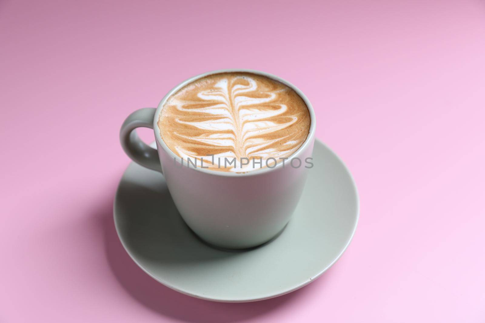 hot cappuccino with latte art isolated in pink background by piyato