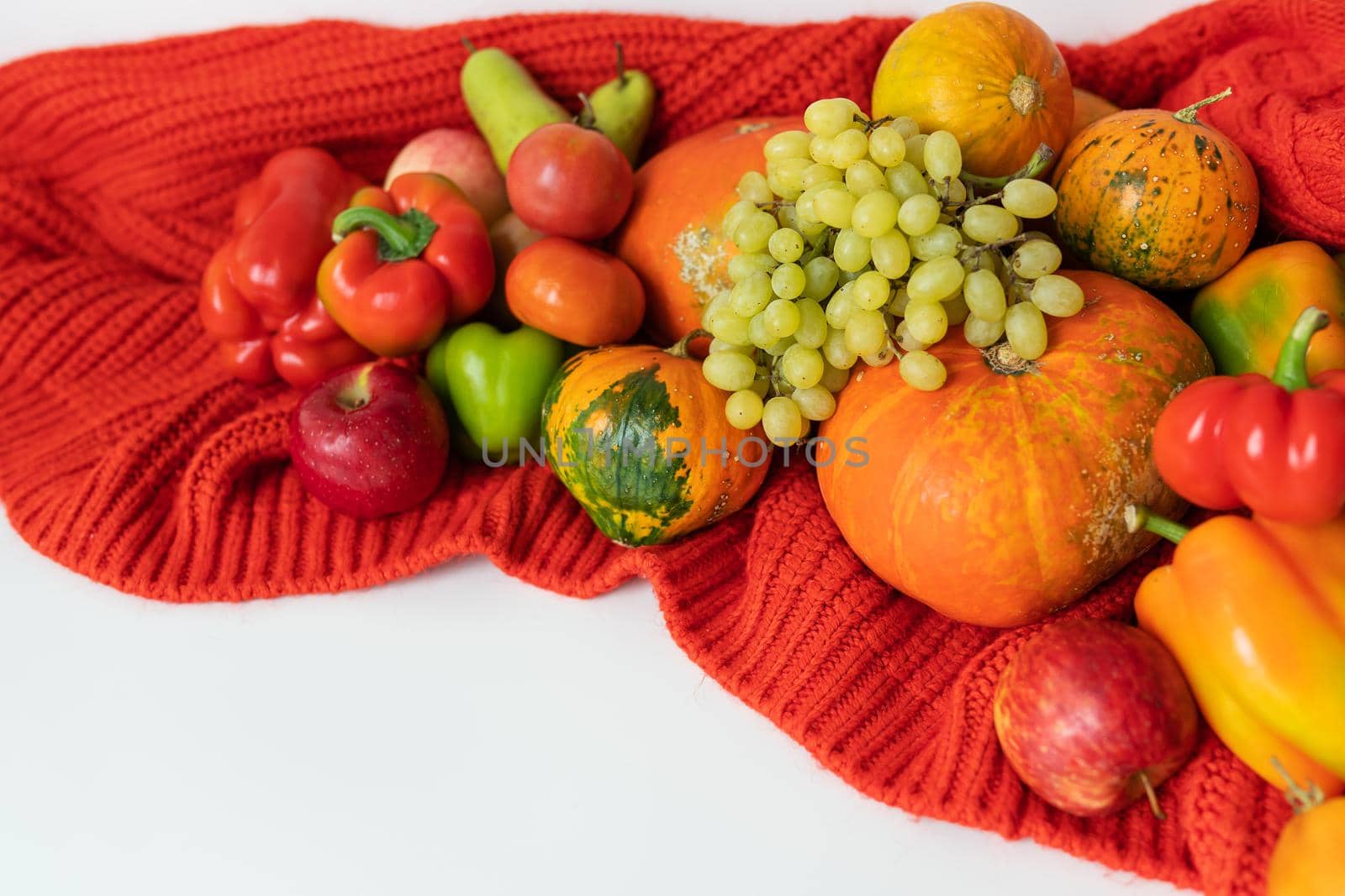 Thanksgiving Day. Big autumn harvest - pear, apples, pumpkin, pepper, tomato on a white background and red cloth. Thanksgiving celebration concept. by sfinks