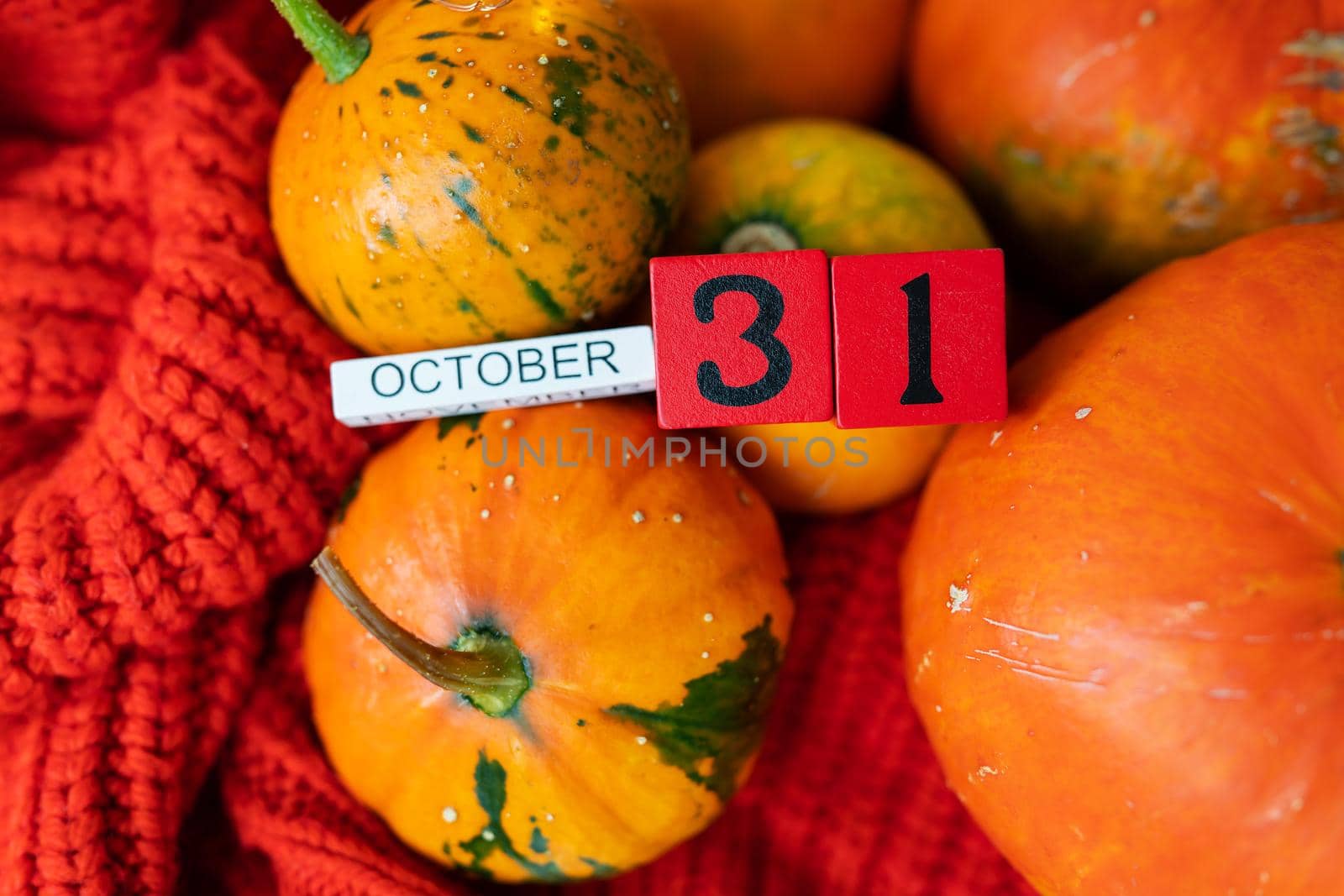 Wooden cube calendar showing October 31st Halloween preparing pumpkins for carving. Holiday and party concept
