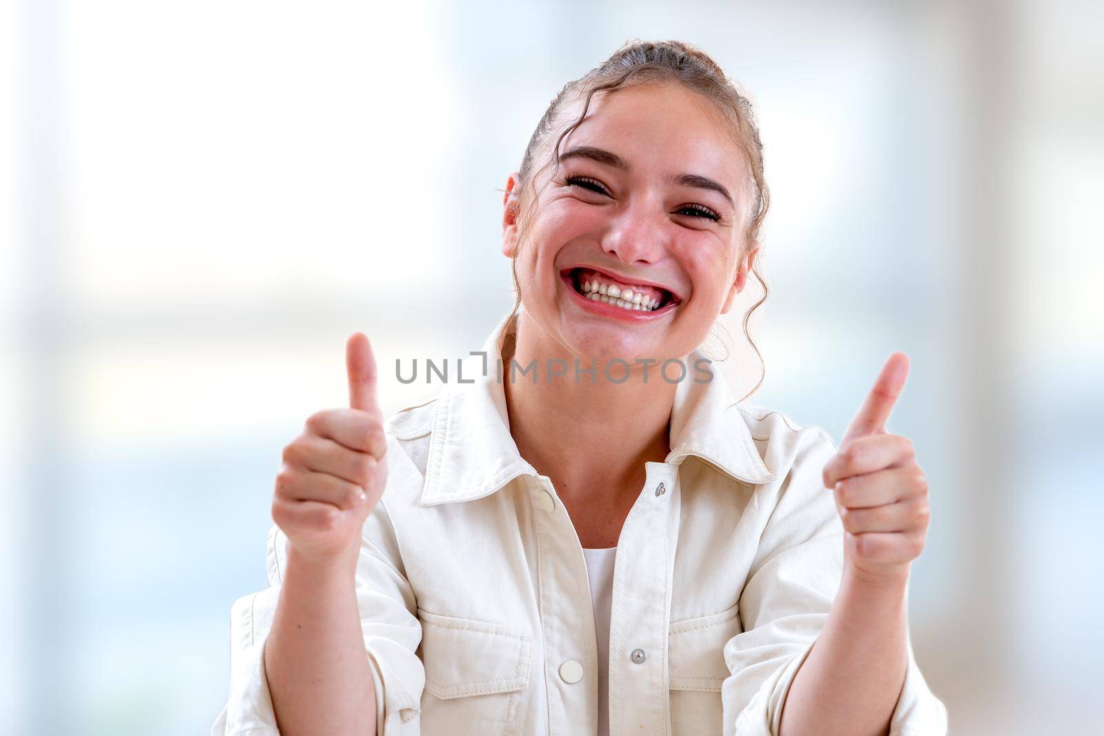 Young woman bursting out laughing on a light and blurry background by JPC-PROD