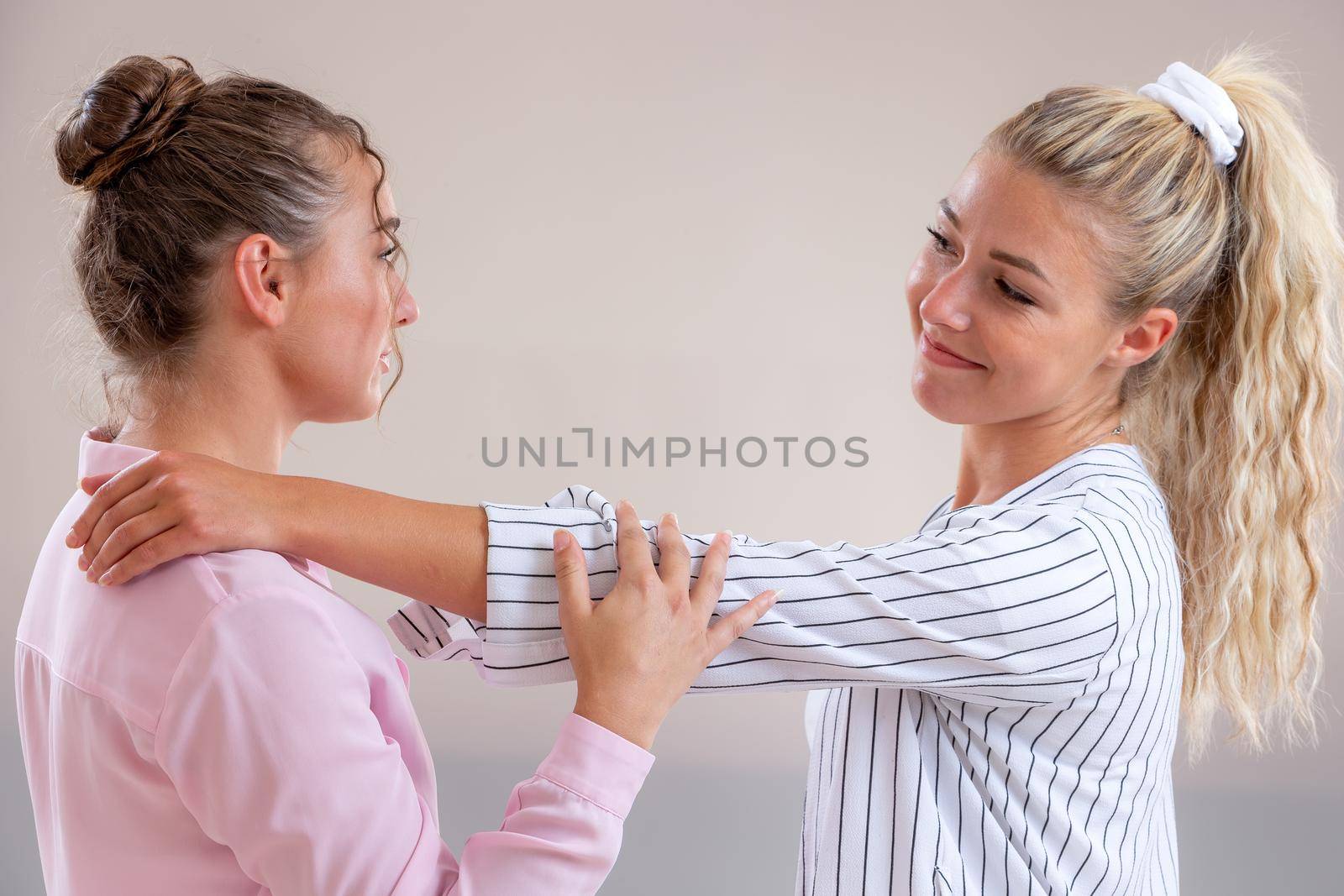 Complicity - young women face to face on a light gray background