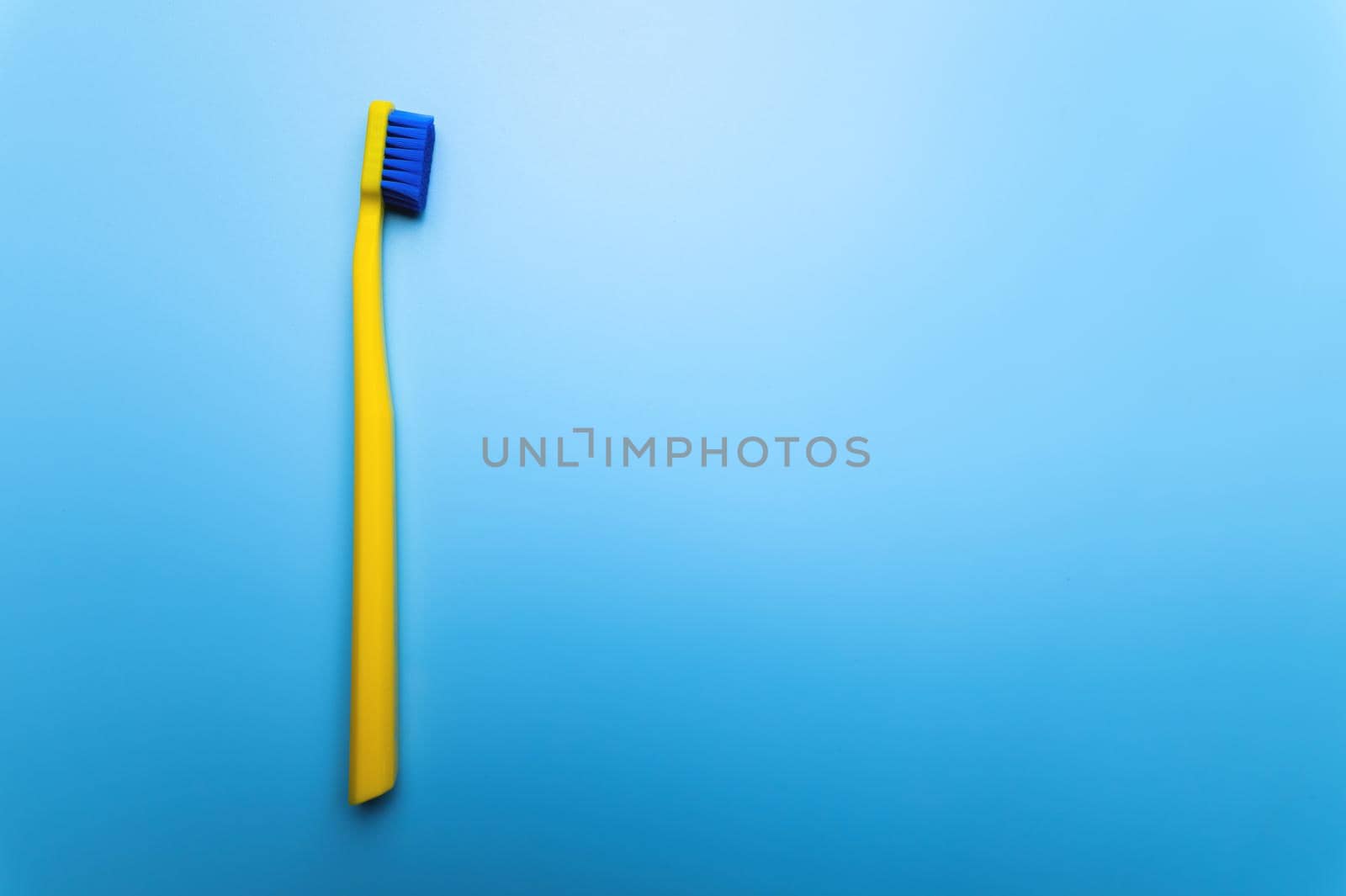 top view close-up of a bright toothbrush, alone, without people, lies on a blue background.