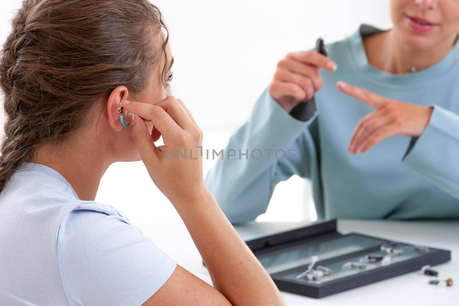 Woman in front of a hearing care professional to test a hearing aid.