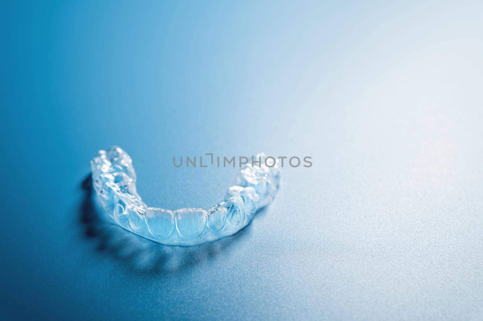 Close up invisible aligners on the blue background with copy space. Plastic braces dentistry retainers to straighten teeth.