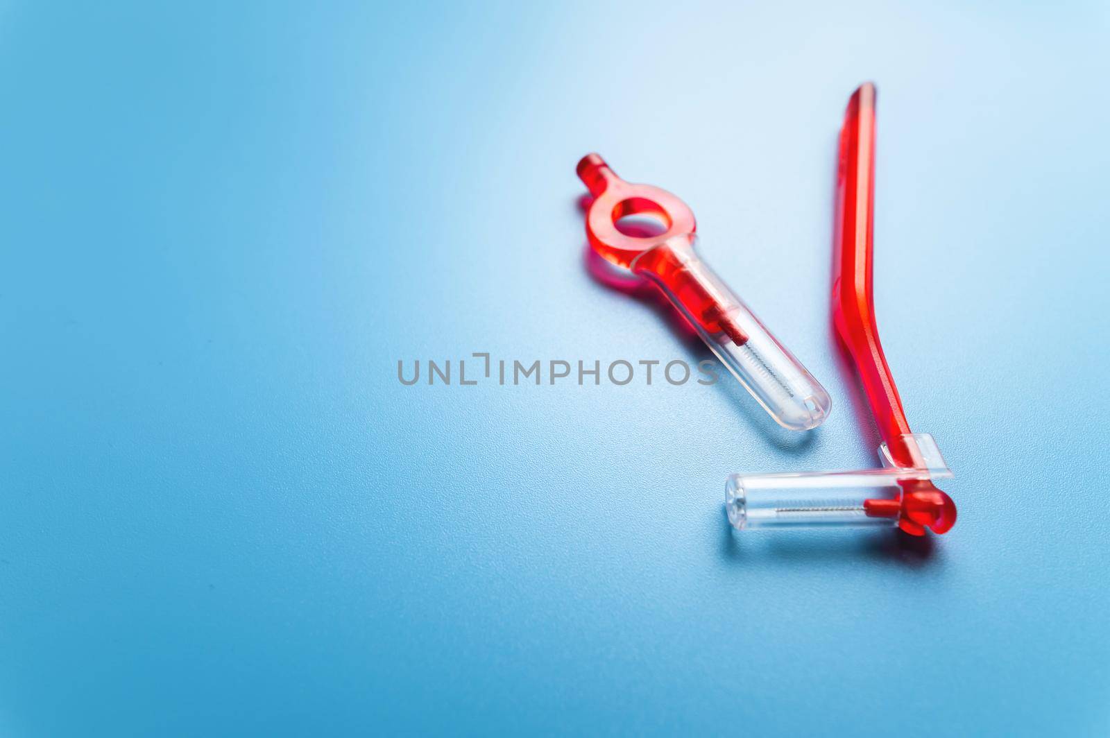 interdental orthodontic brushes for teeth of red color lie on a blue background with free space for your text. dental clinic banner by yanik88