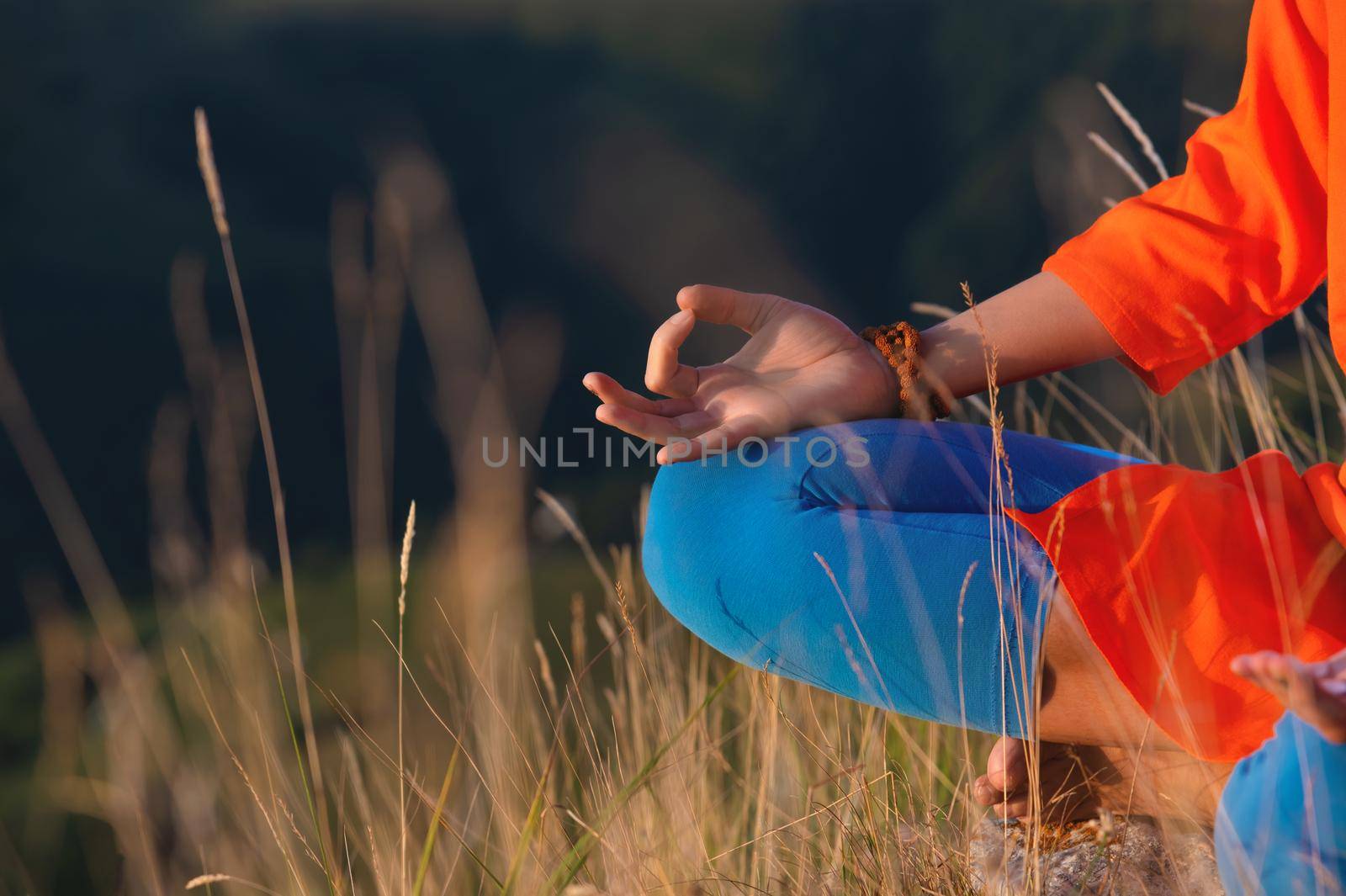 close-up, woman's hand in the lotus position in the grass in the mountains, meditation and relaxation.