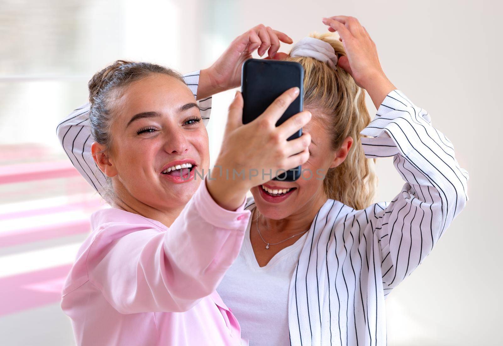 Two young women taking a selfie bursting out laughing-light and blurry background.