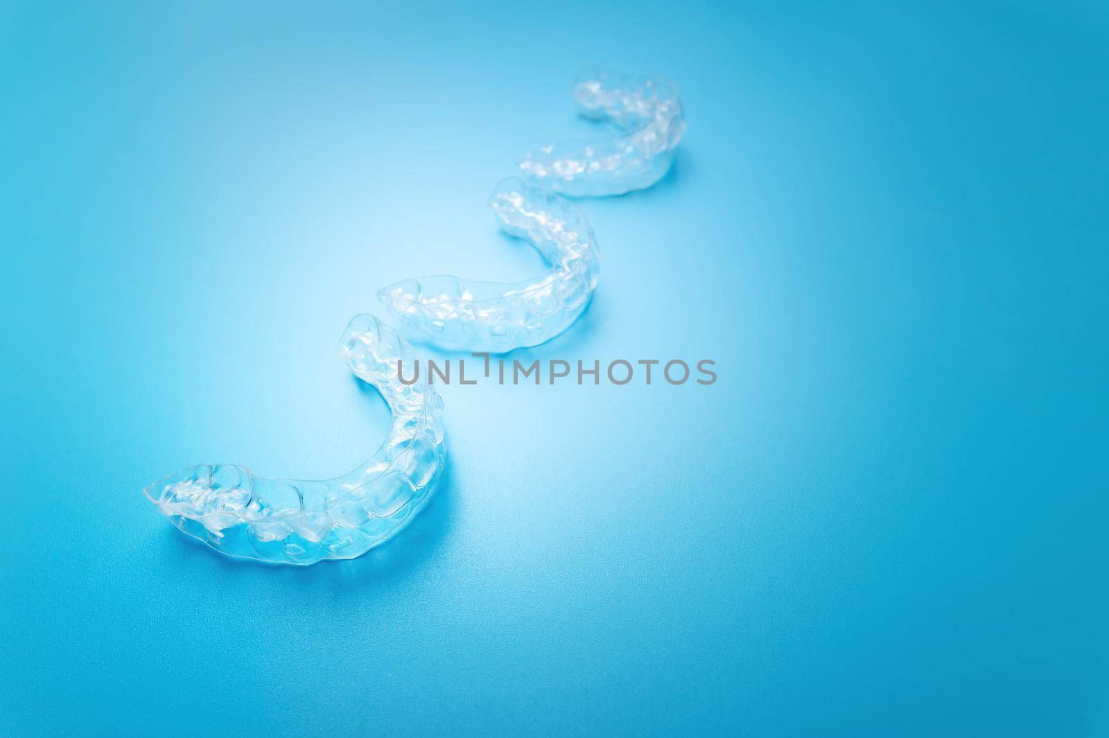 close-up, new transparent braces lie in a row on a blue background. suitable for dental clinic banner.