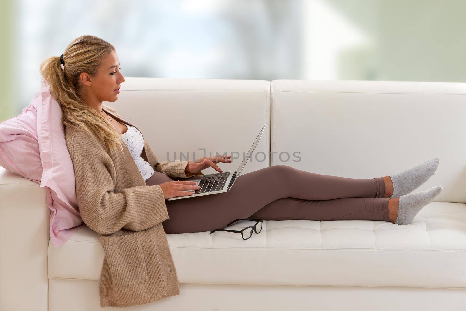 Telecommuting - young woman sitting with her legs lying on the couch by JPC-PROD