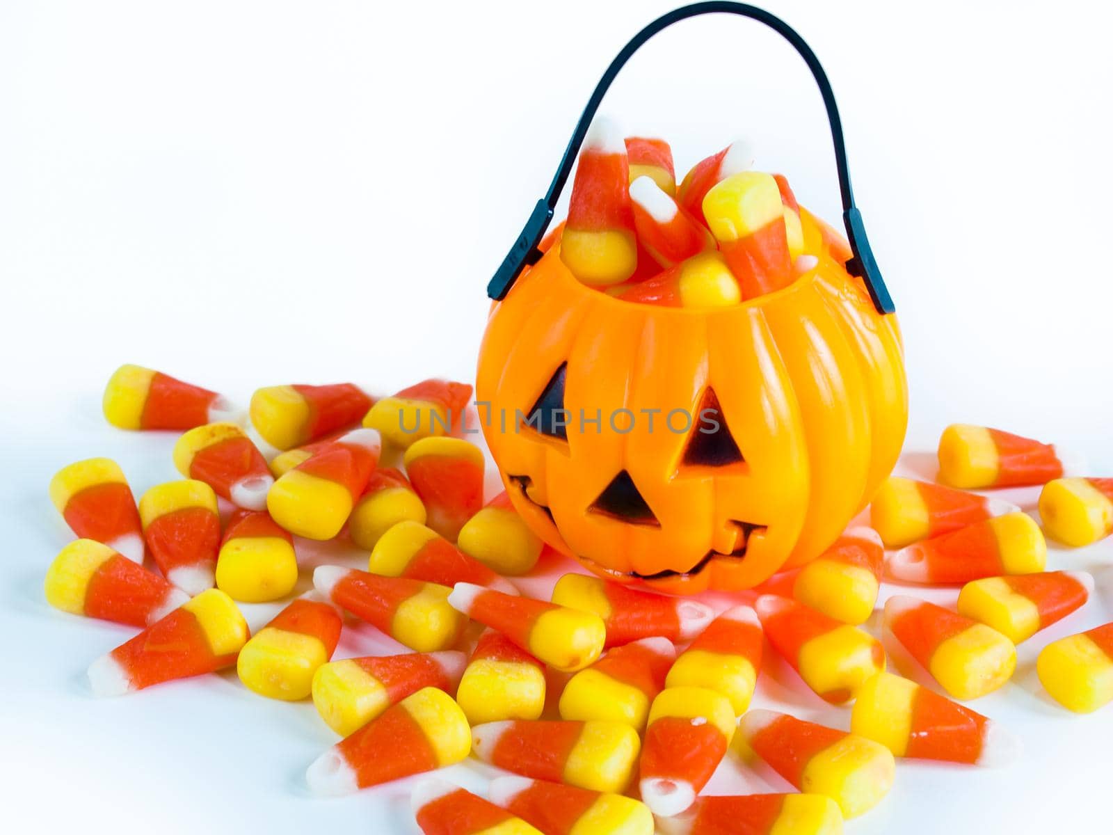 Halloween treat bag filled with candy corn candies on white background.