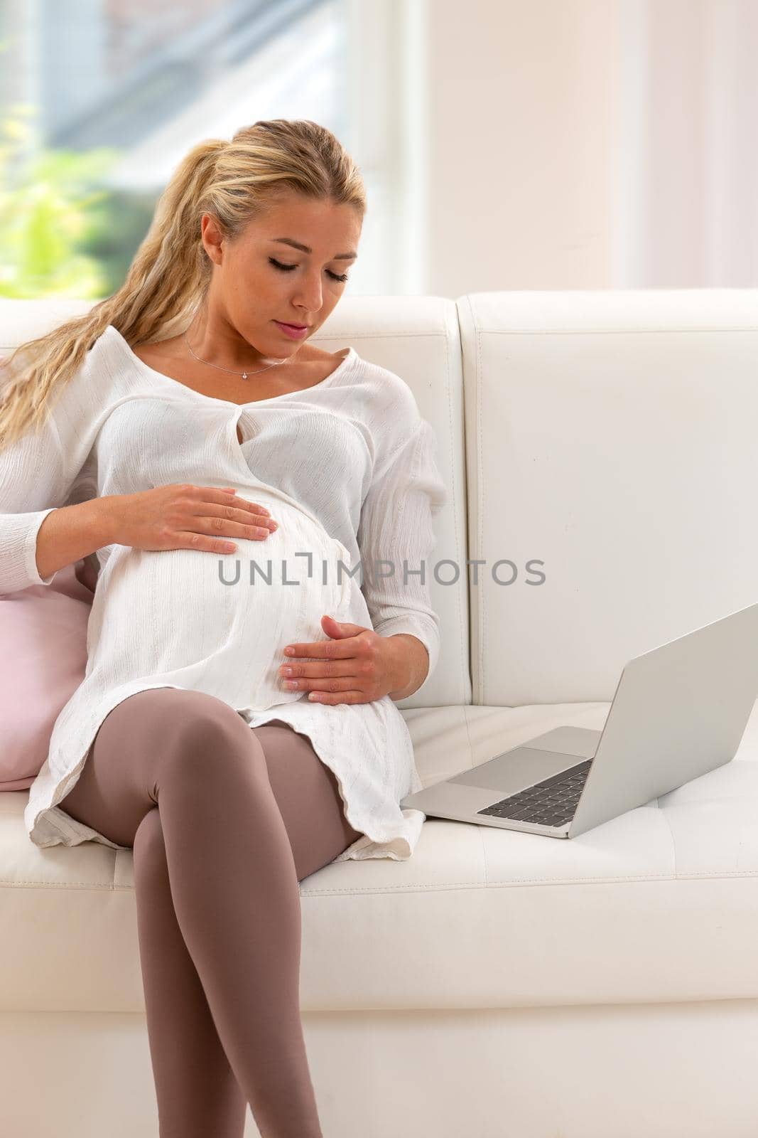 Young woman resting on the sofa, her hands on her stomach.