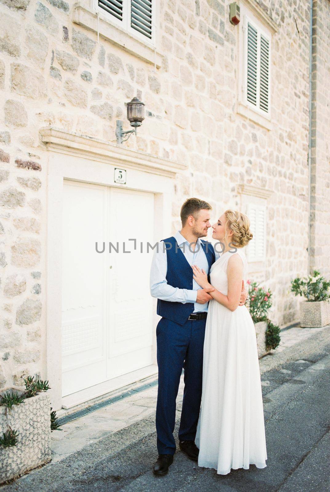 Bride and groom embracing standing near an old stone house. High quality photo