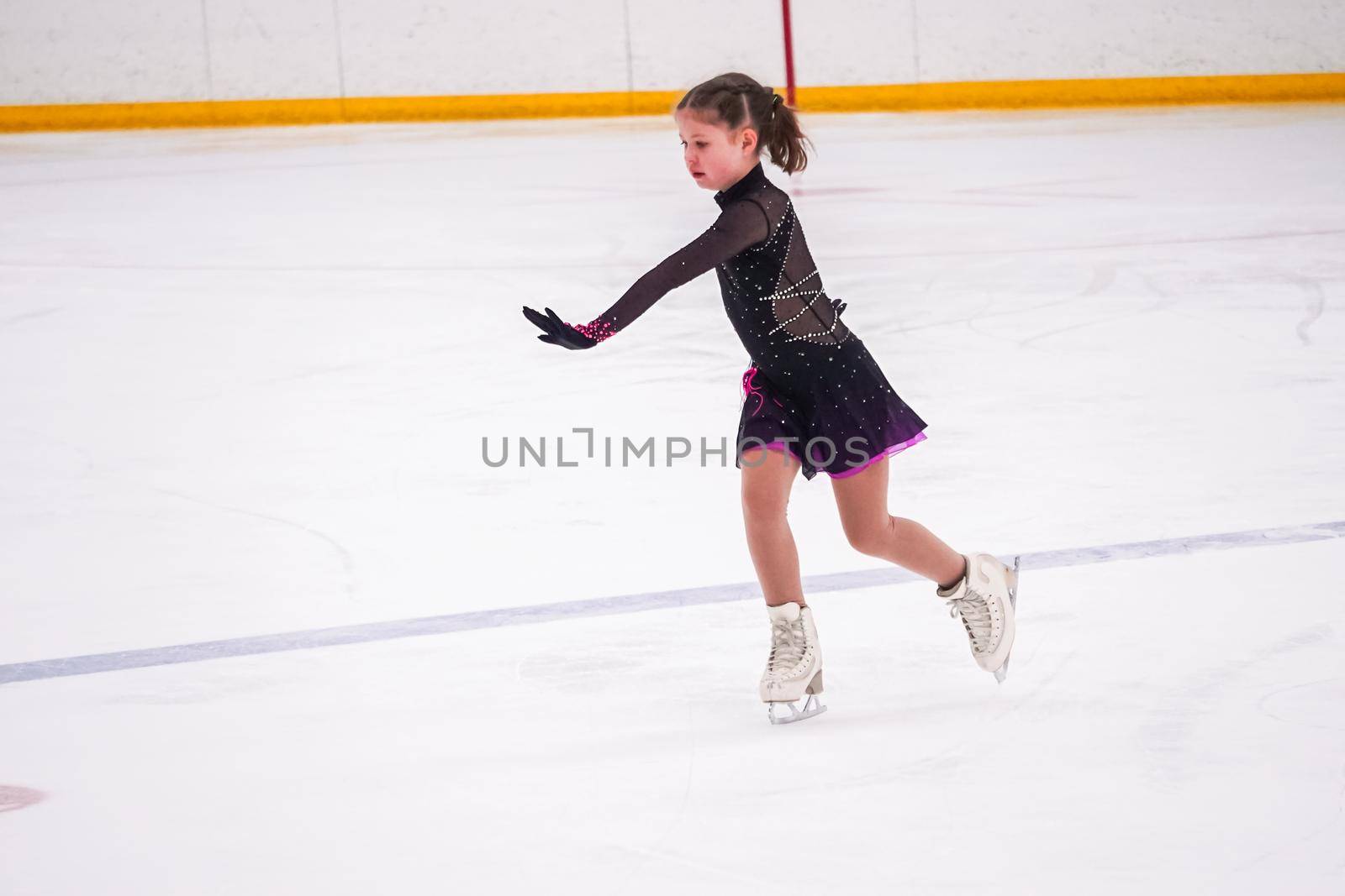 Little girl practicing before her figure skating competition at the indoor ice rink.