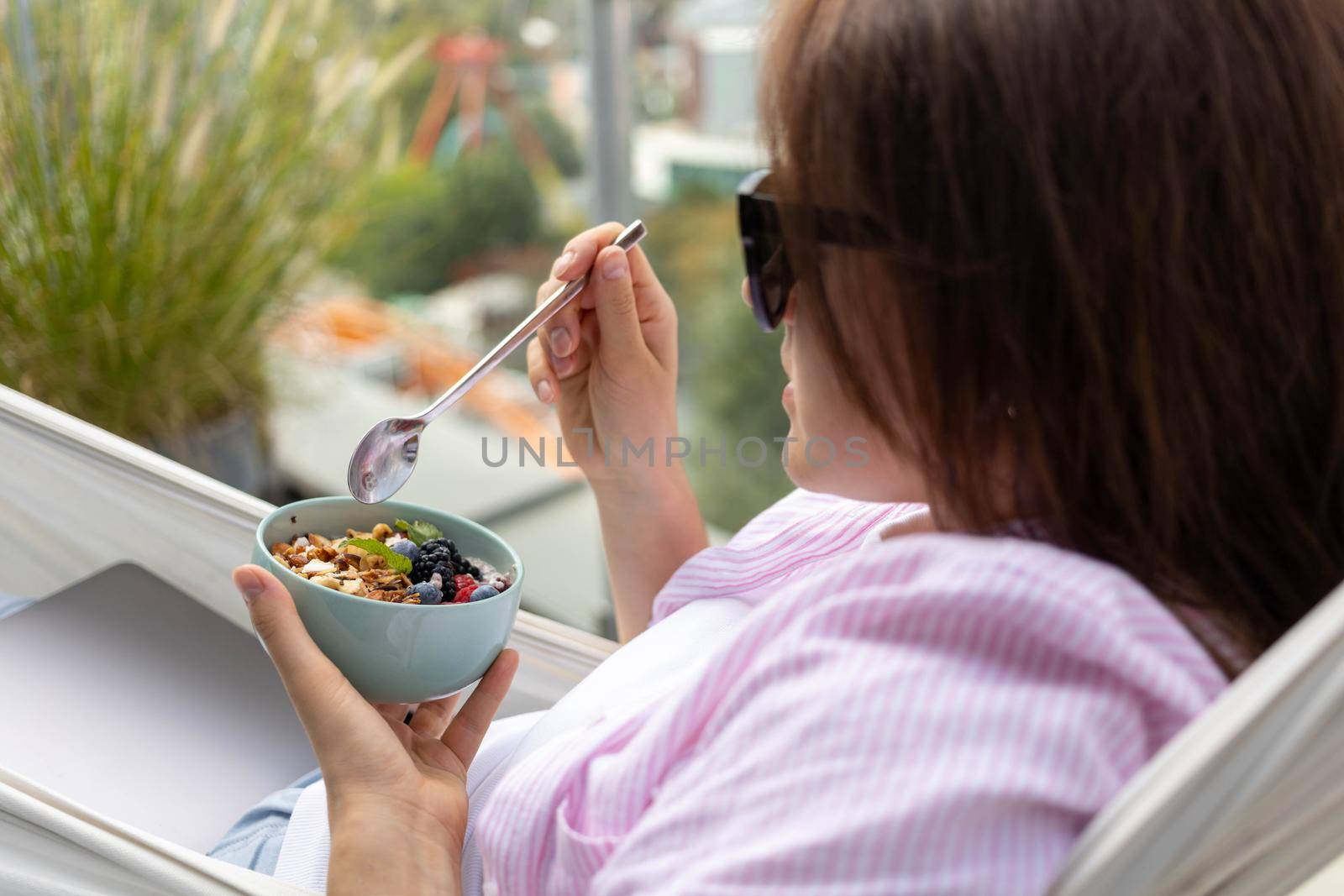 young woman eating chia pudding with nuts and berries by Chechotkin