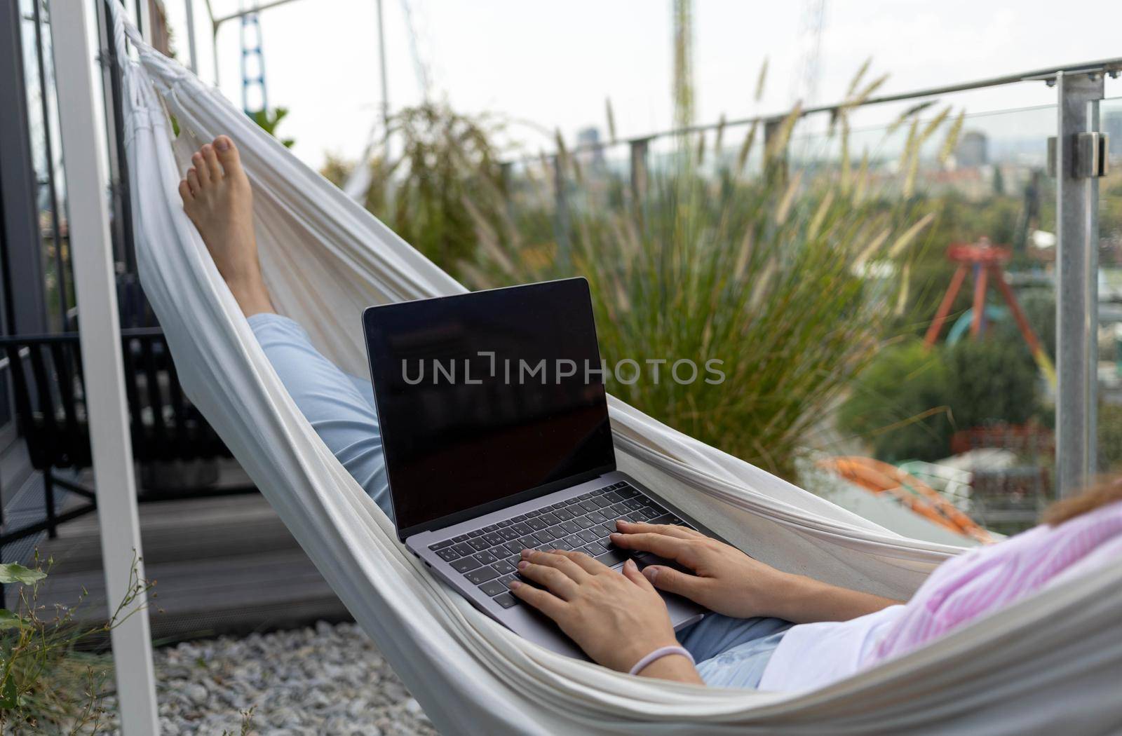 young woman freelancer working in hammock on the terrace. High quality photo