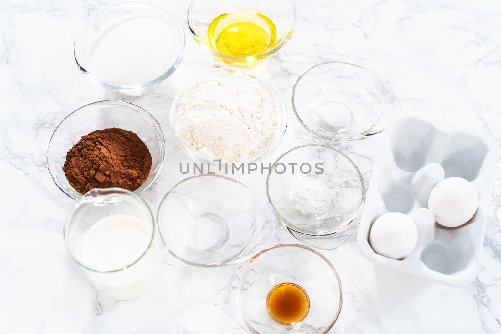 Measured ingredients in glass mixing bowls to prepare chocolate cupcake.