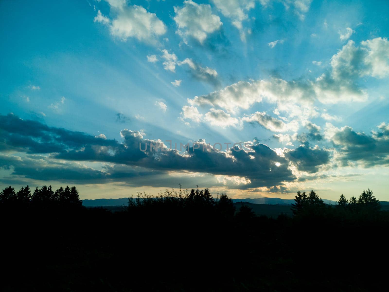 Beautiful shining sun behind big clouds at sunset over big fields by Wierzchu