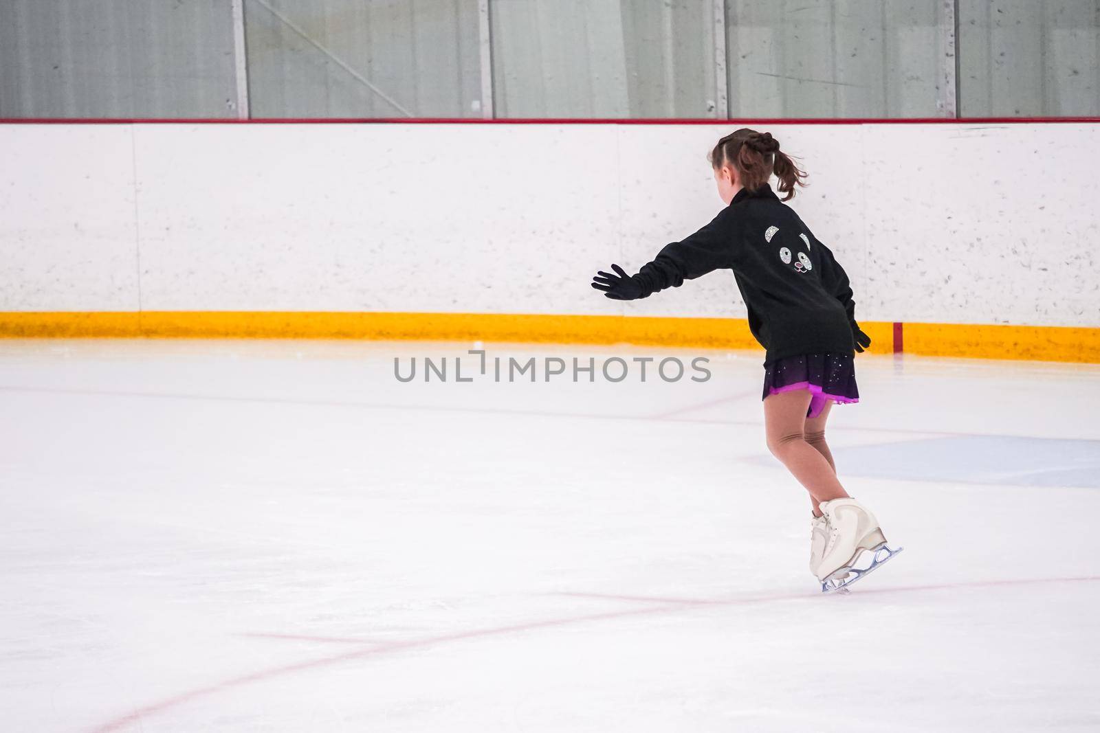 Little girl practicing before her figure skating competition at the indoor ice rink.