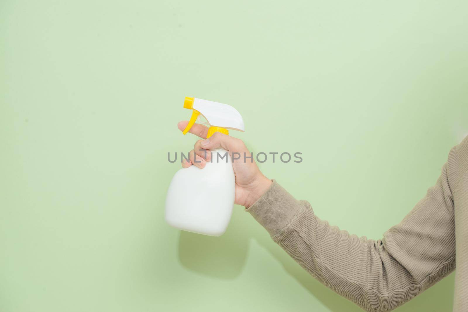 Male hand with sprayer isolated on green background by makidotvn