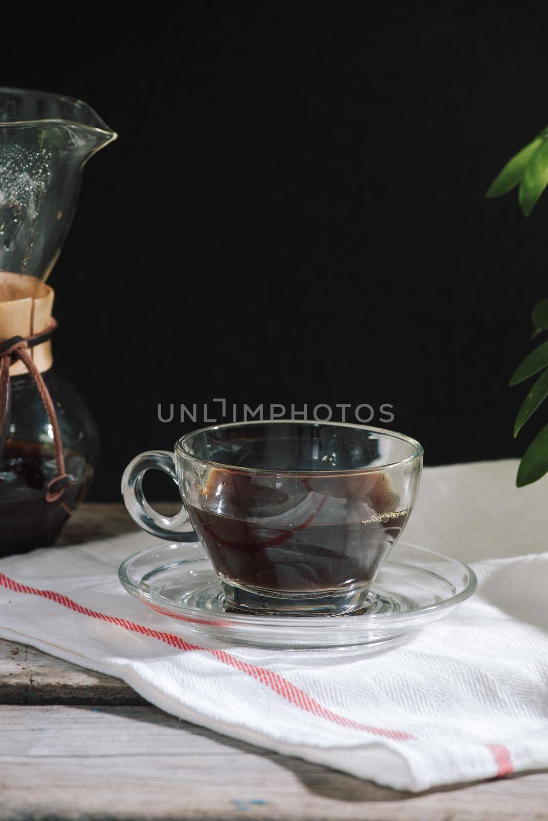 Drip brewing coffee concept. Wooden desk with chocolate cake and cup of coffee on black background. 
