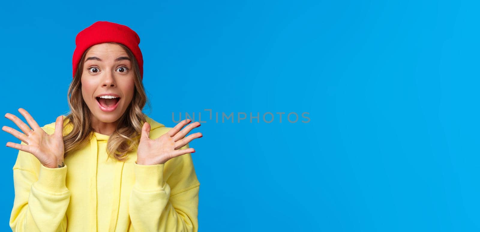 Excited good-looking european female explain great news, talking to friend astonished, shaking hands thrilled and looking camera fascinated, standing blue background in red beanie by Benzoix