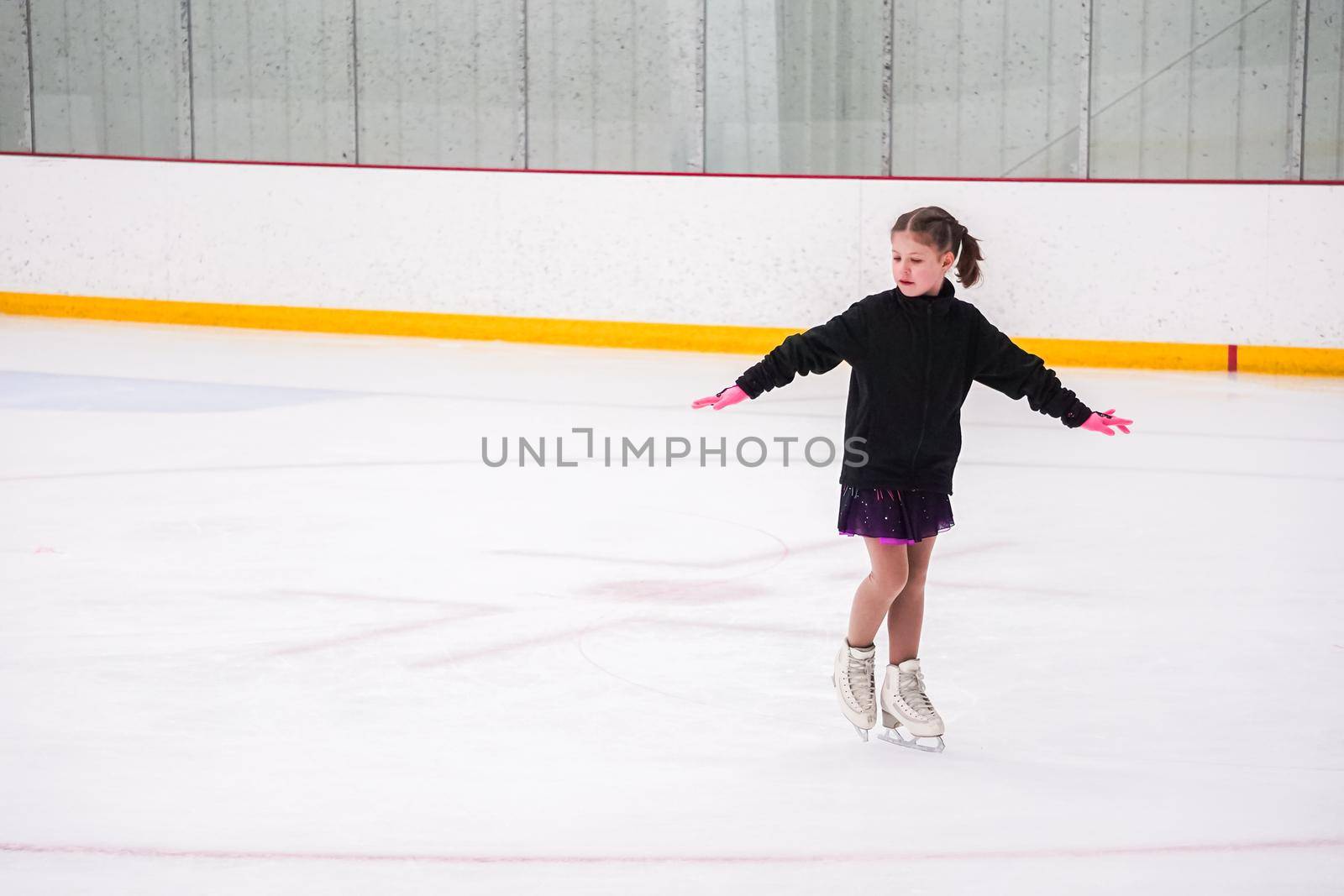 Little girl practicing before her figure skating competition at the indoor ice rink.