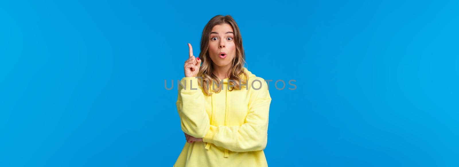 Got an idea. Excited creative and smart blond caucasian woman have suggestion, show eureka gesture with index finger raised up, talking to team, made-up plan, stand blue background.