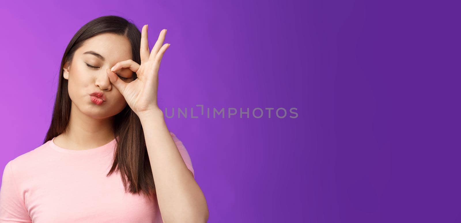 Cute silly asian female brunette folding lips kiss lovely expression, close eyes dreamy send muah, show perfection, okay ok sign, stand purple background carefree and cheerful. Copy space