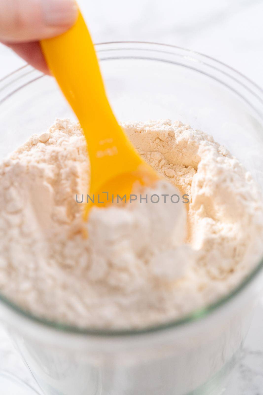 Glass jar with all-purpose flour and measuring spoon in it.