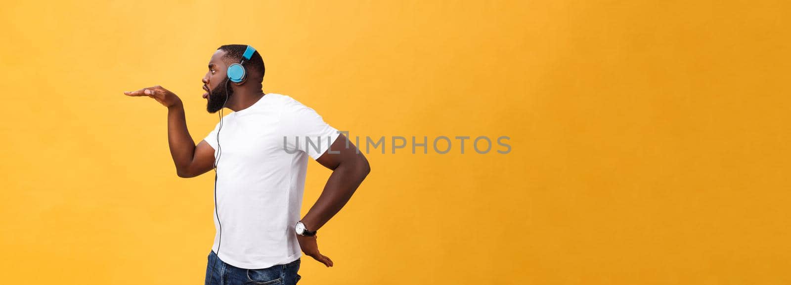 Young African American man wearing headphone and enjoy music dancing over yellow gold Background by Benzoix