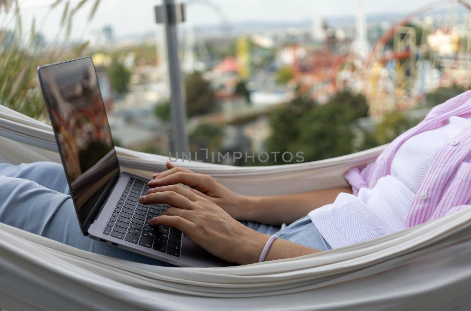 young woman freelancer working in hammock on terrace by Chechotkin