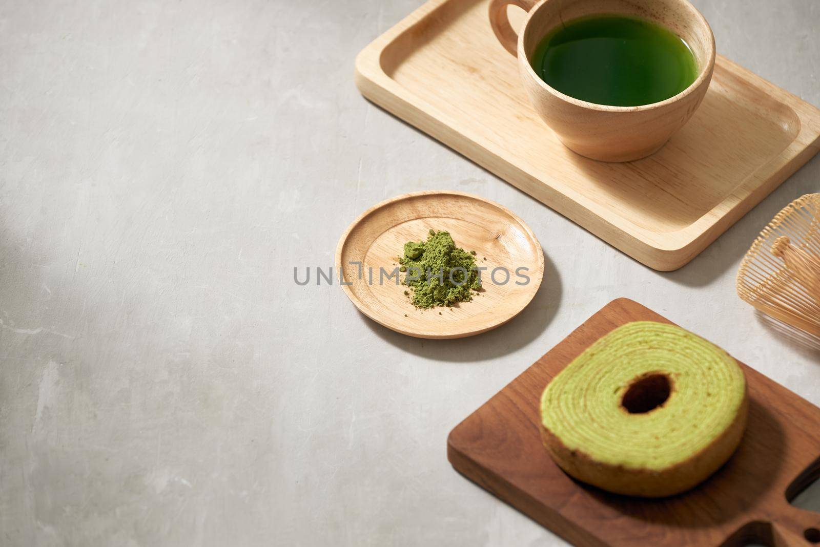 Green tea matcha in a wooden cup with German cake on the brown mat close-up