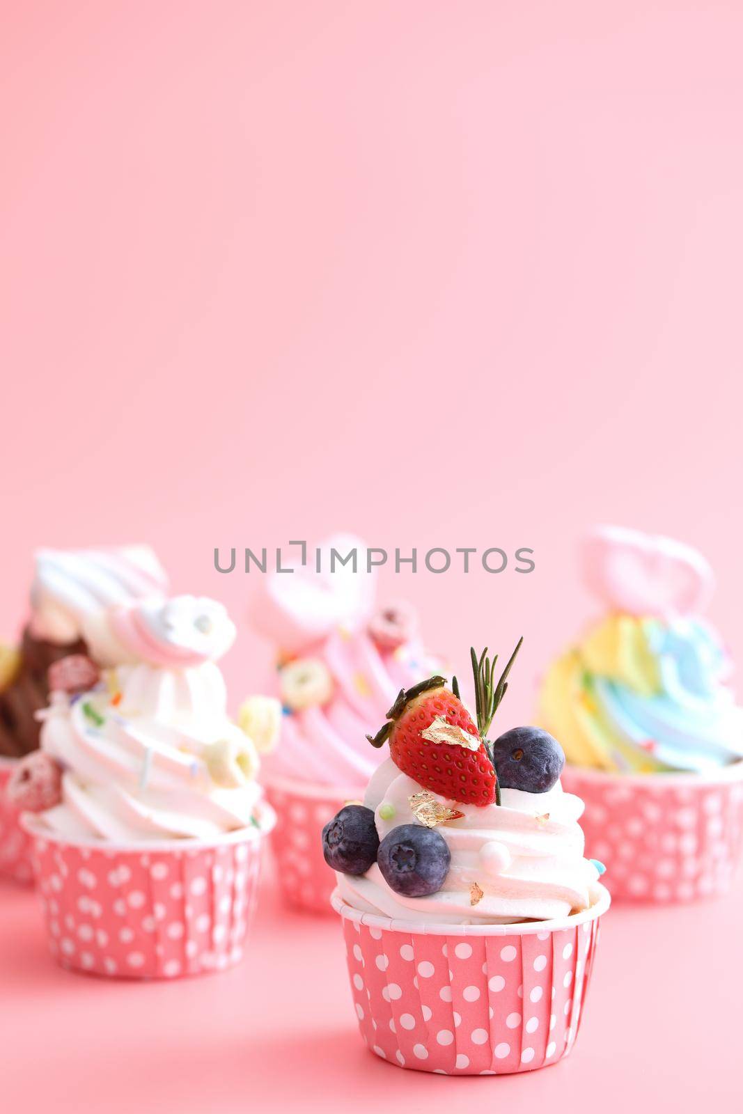 Colorful cupcakes isolated in pink background by piyato