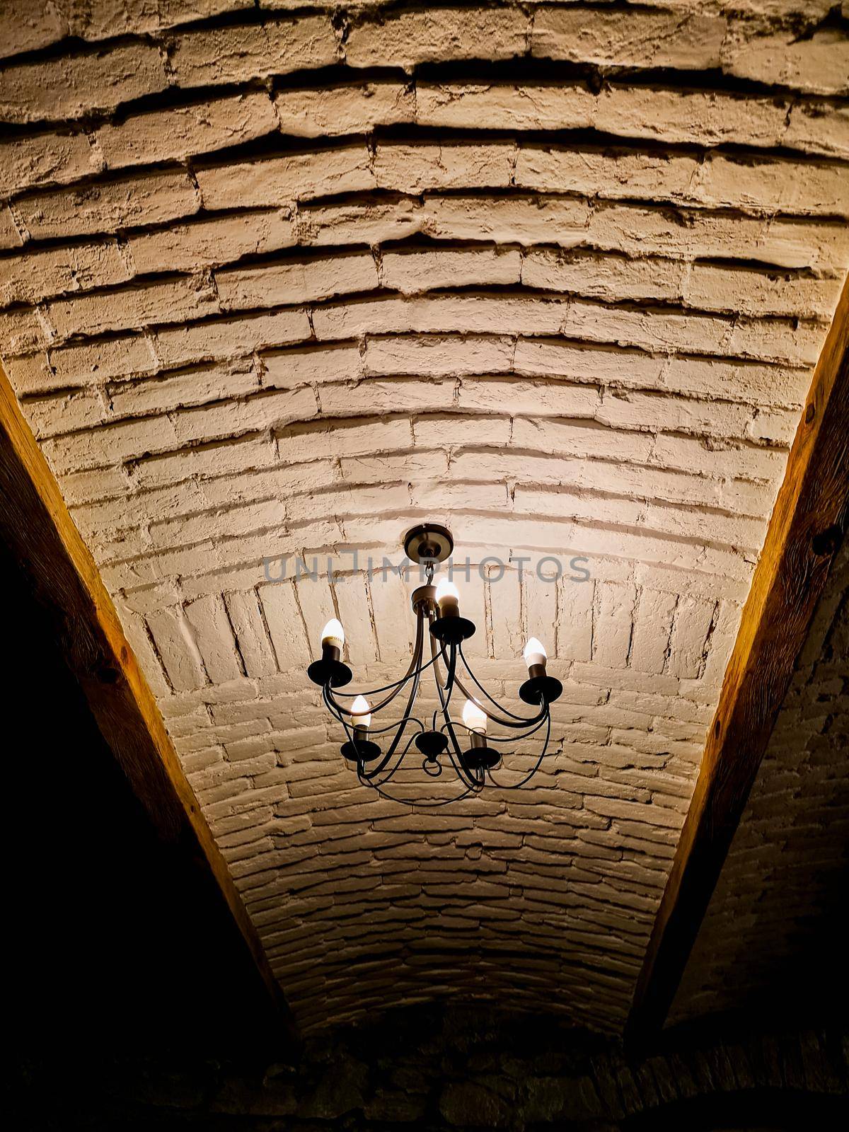 Looking up to white brick ceiling with old chandelier