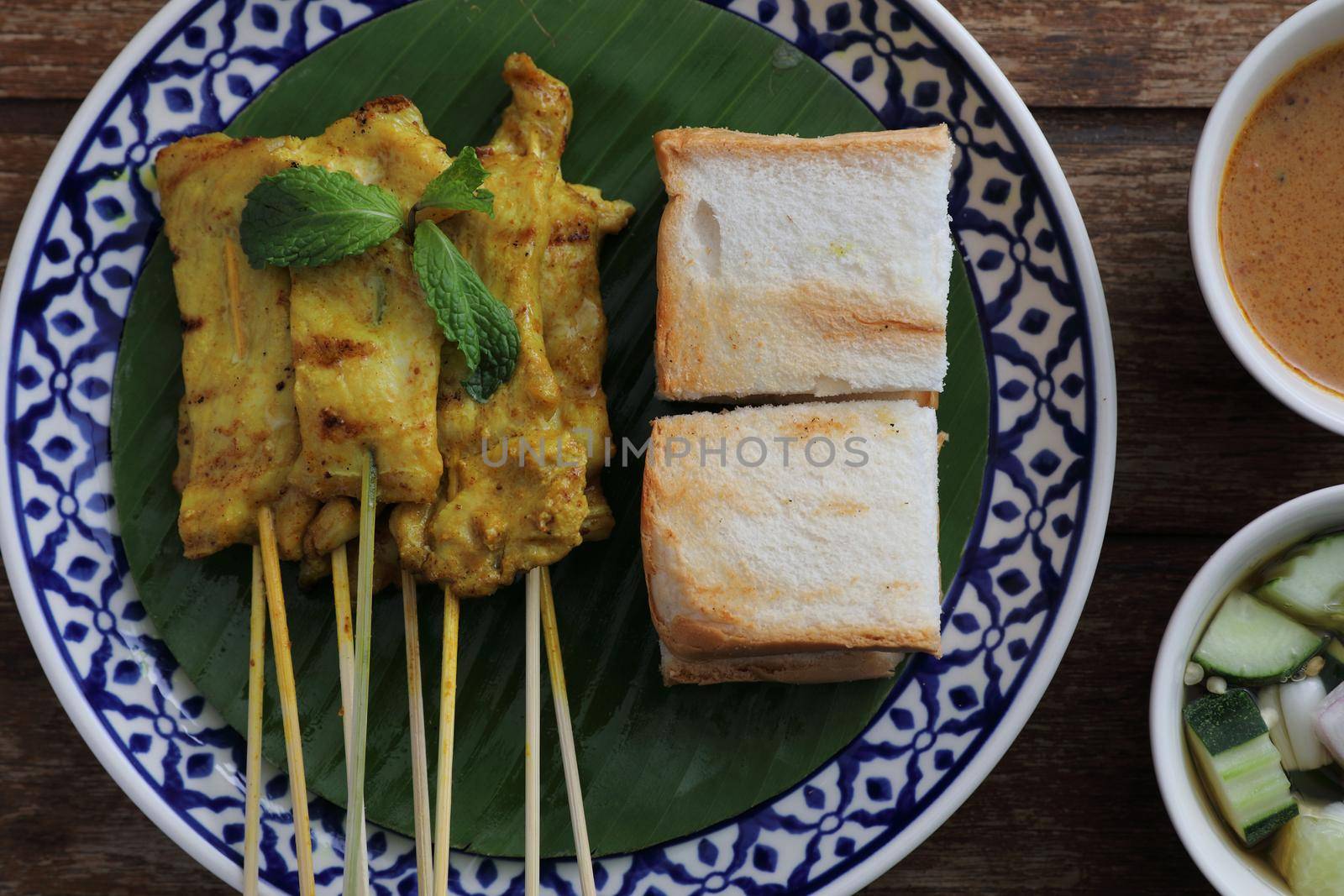 Local Thai food pork satay with oeanut dipping sauce isolated in wood background by piyato