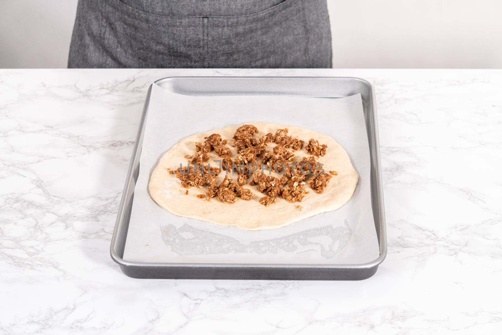 Preparing cinnamon dessert pizza on a baking sheet lined with parchment paper.