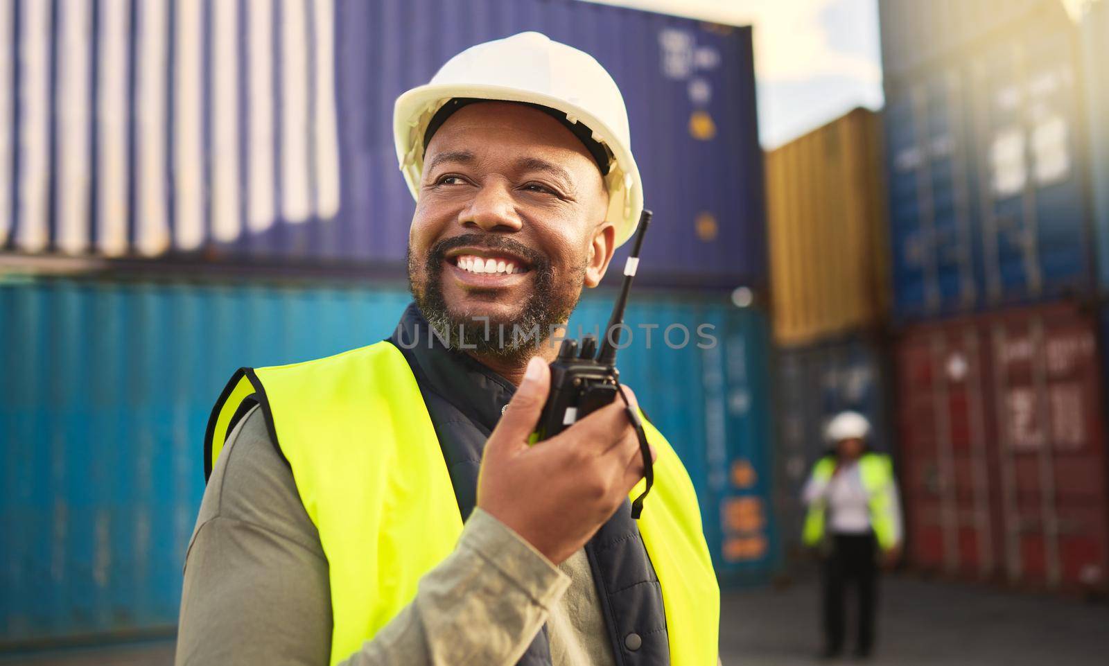 Man in logistics talking on radio, communication in shipping and transportation industry with a smile. Organization of commercial cargo, e-commerce containers and supply chain management of shipyard.