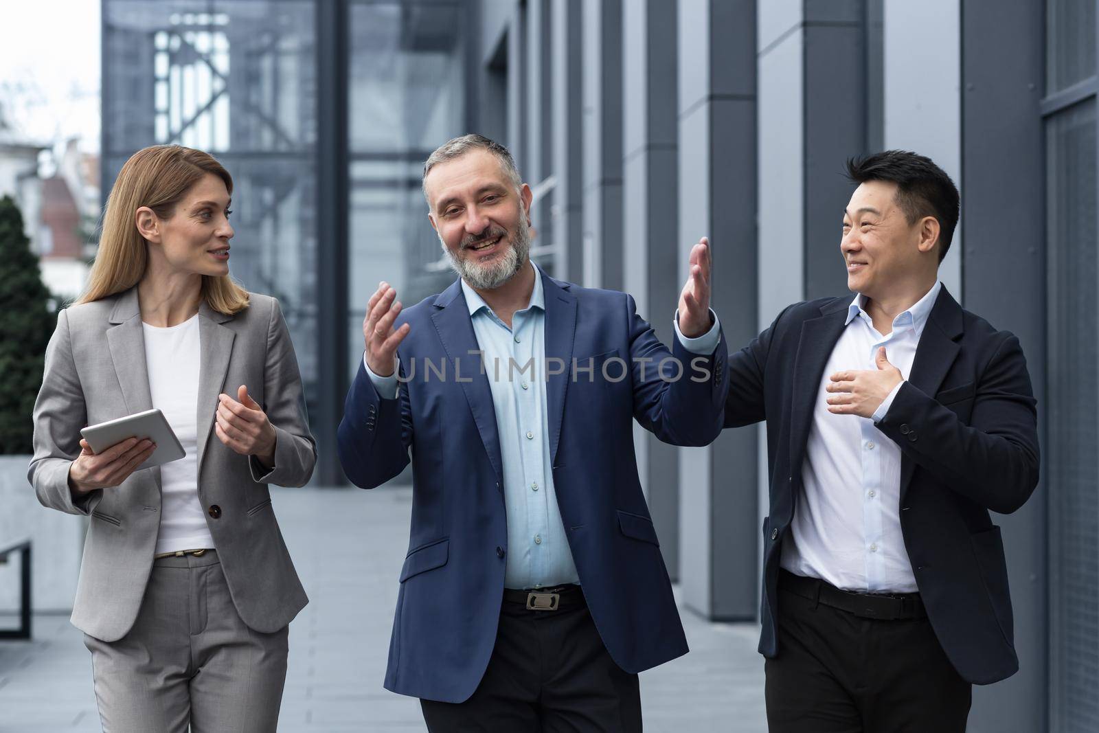 A diverse team of IT specialists, senior and experienced engineers managers team leaders, a group of three workers happily strolling outside an office building, colleagues in business suits by voronaman