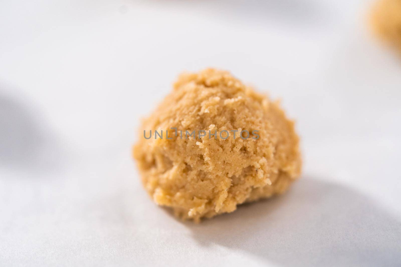 Scooping cookie dough with dough scoop into a baking sheet lined with parchment paper to bake eggnog cookies with a chocolate gingerbread man.