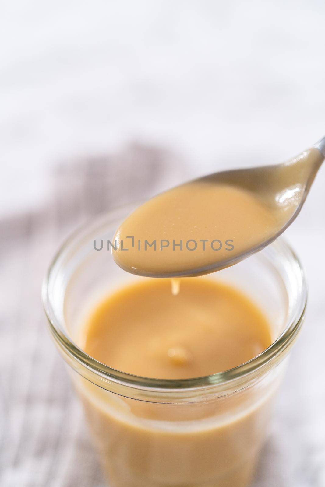 Homemade toffee glaze in a glass jar on the kitchen counter.