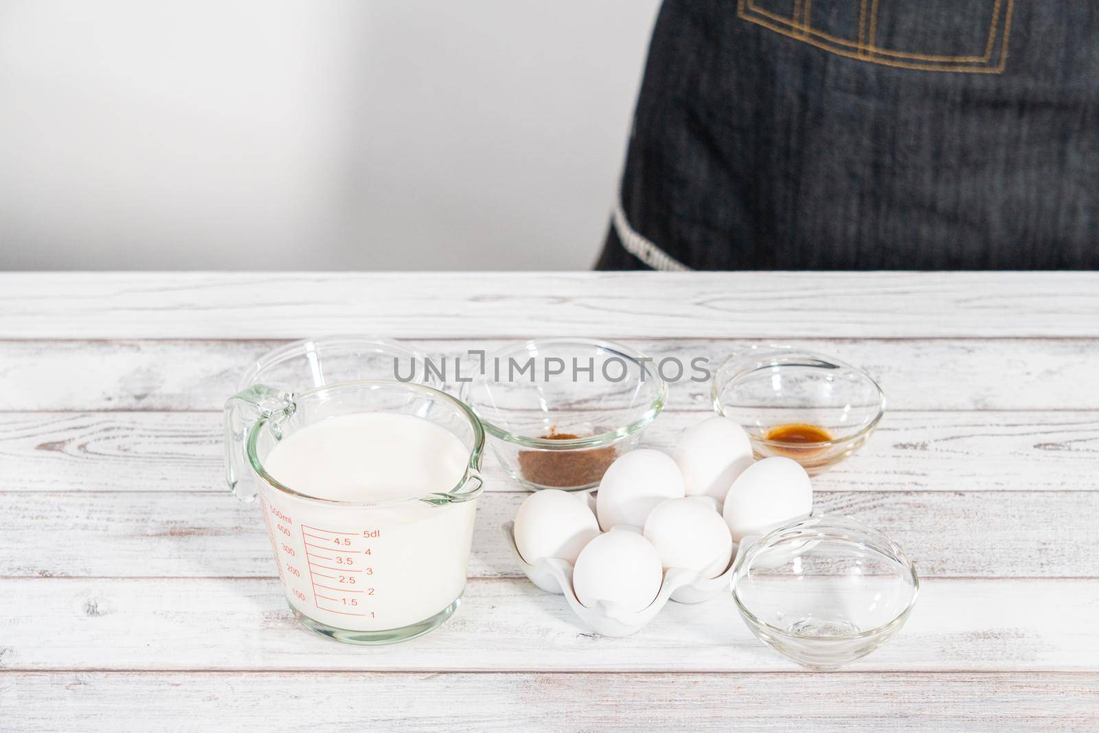 Ingredients in glass mixing bowls to prepare french toast on a wooden table.